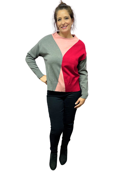 Woman wearing a color-blocked sweater with gray, pink, and red sections on a white background.