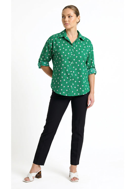 Woman wearing a green patterned shirt and black pants on a white background