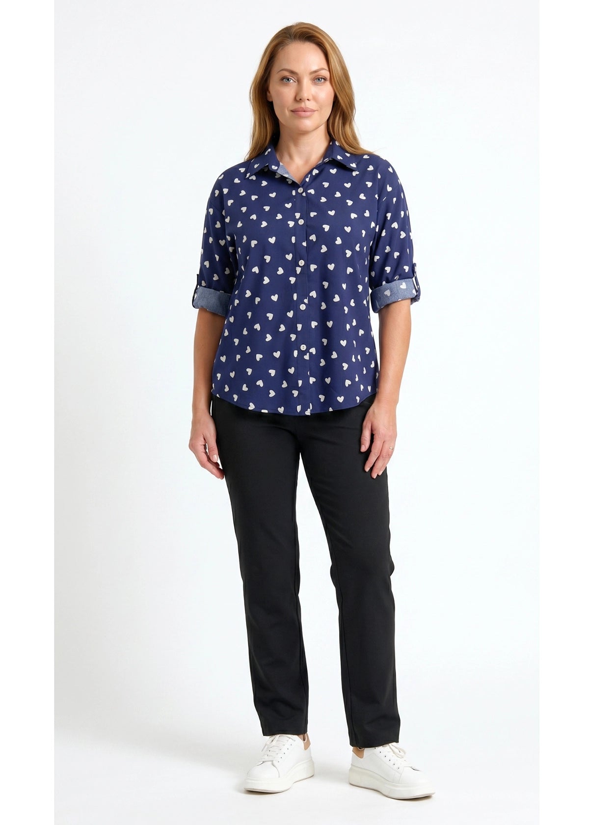 Woman wearing a navy blue patterned shirt and black pants on a white background