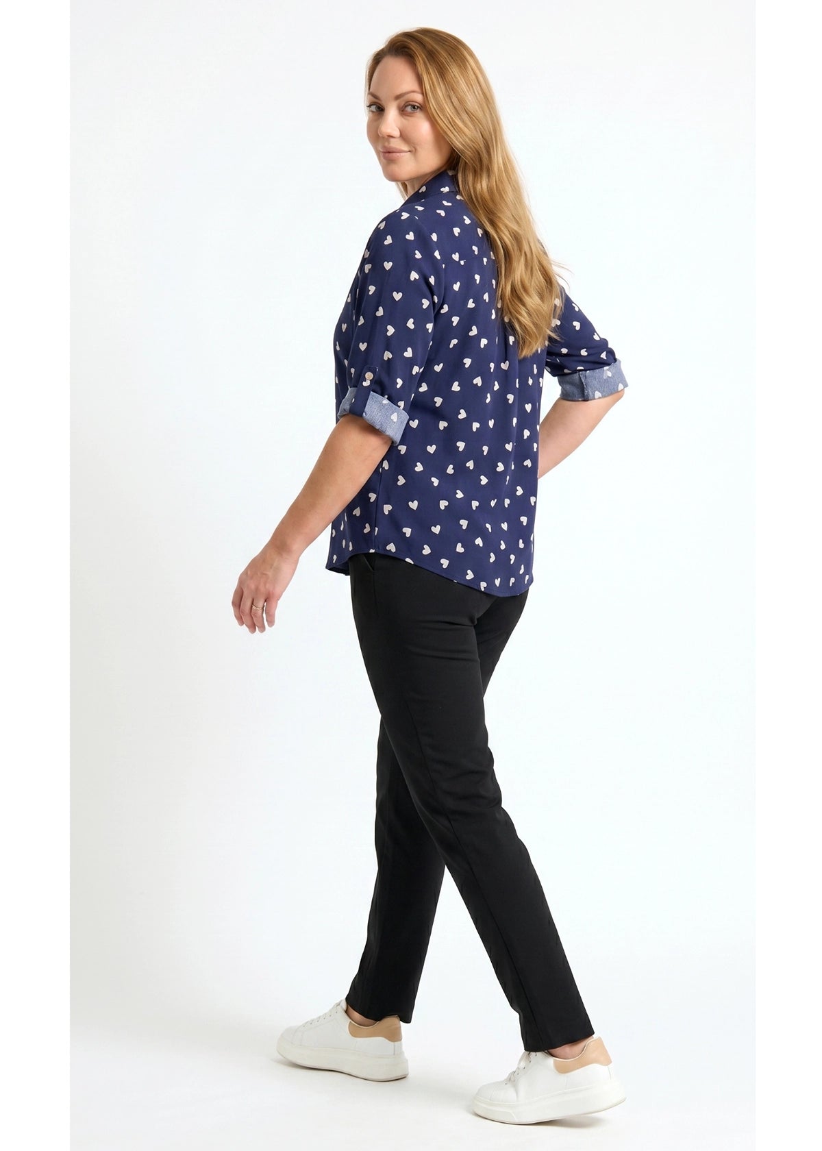 Woman wearing a navy blue patterned shirt and black pants on a white background