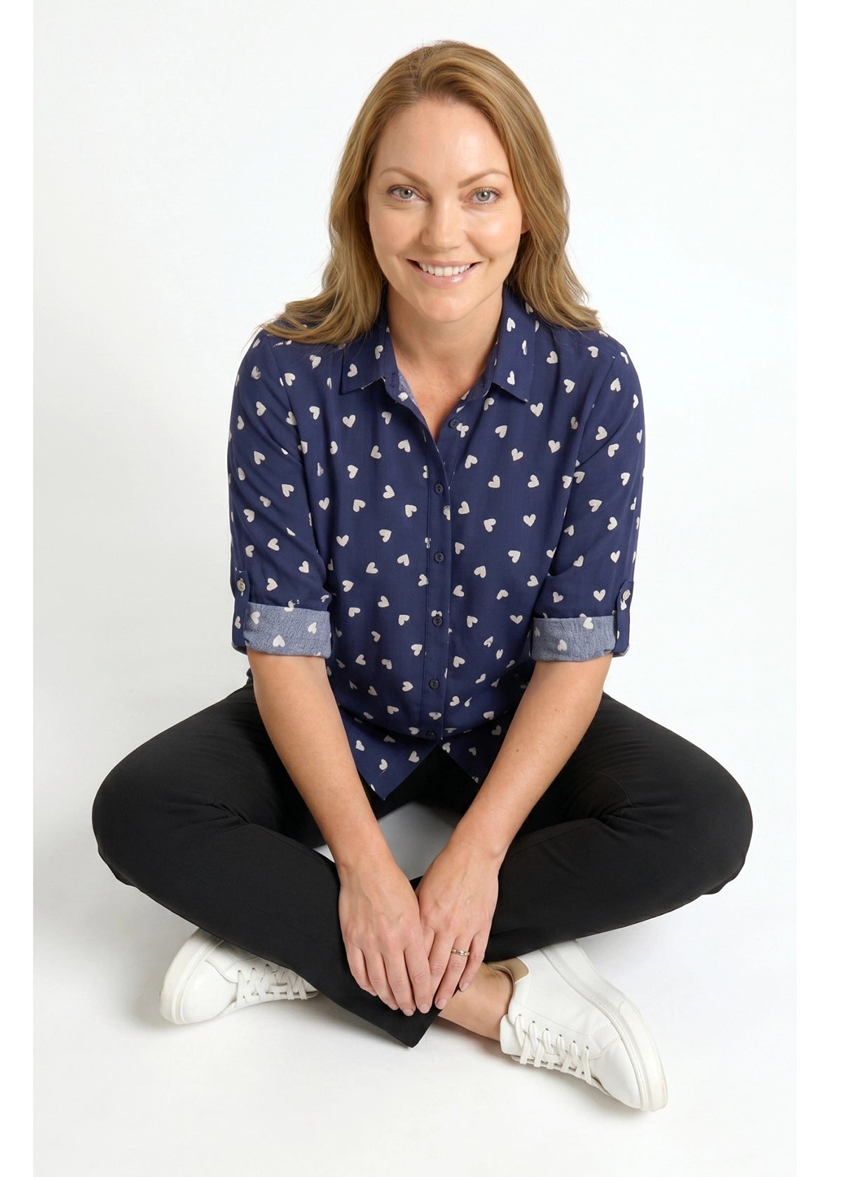 Woman wearing a navy blue patterned shirt sitting on a white background