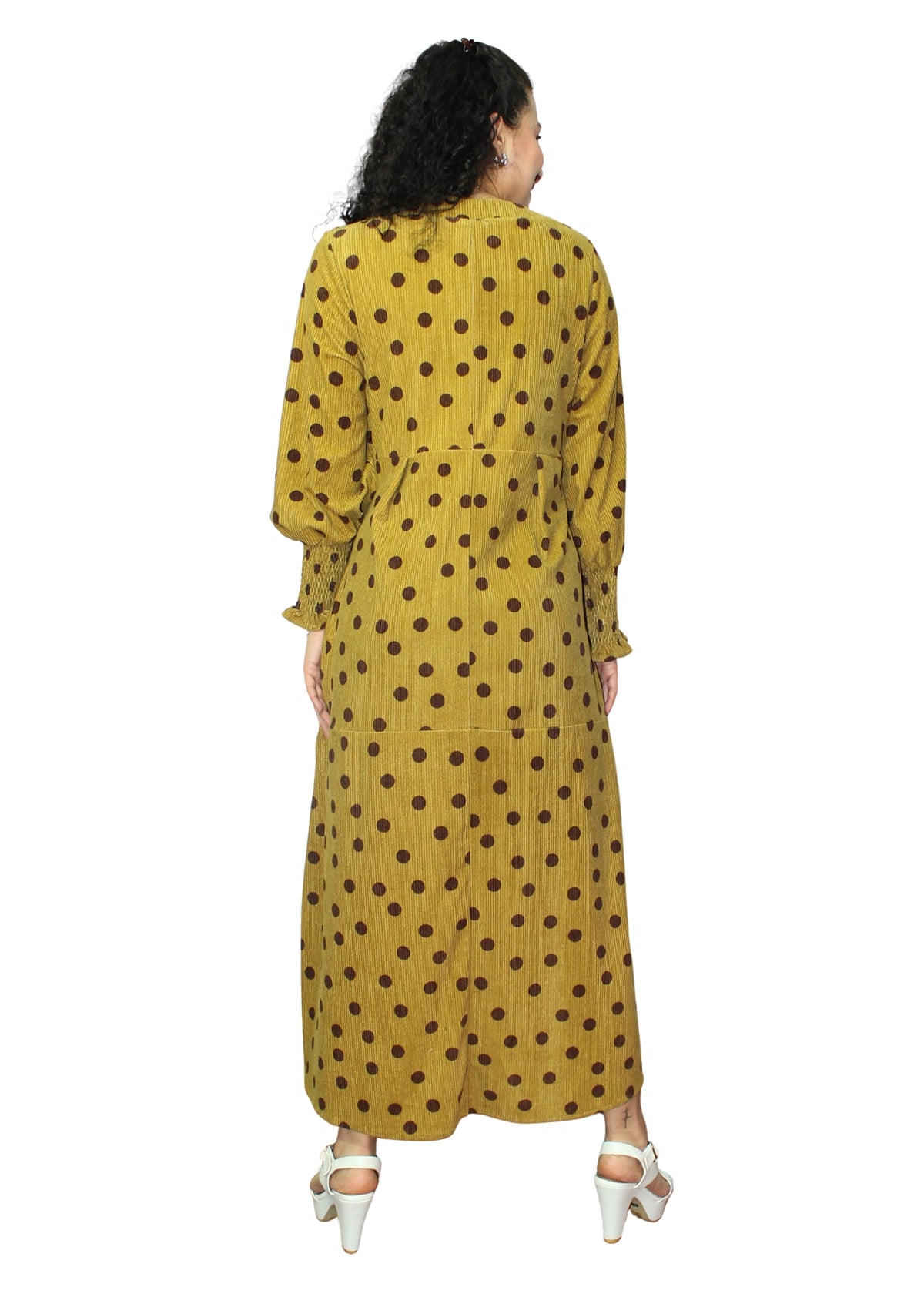 Woman wearing a yellow dress with brown polka dots on a white background