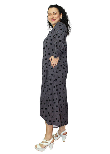 Woman wearing a long, dark gray dress with black polka dots on a white background