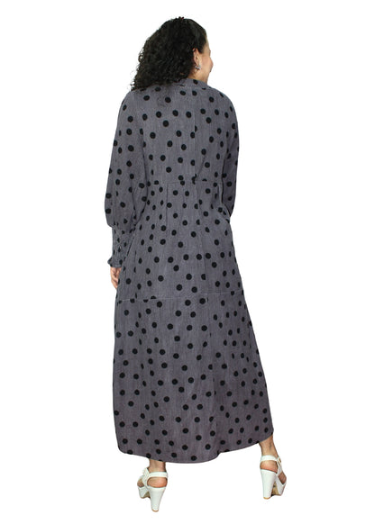 Woman wearing a long, dark gray dress with black polka dots on a white background