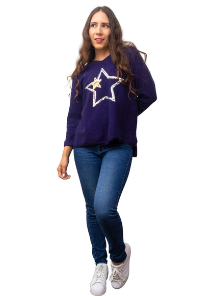 Woman wearing a purple sweater with a star design and blue jeans on a white background