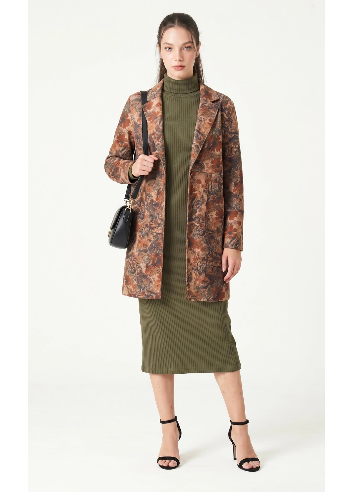 Woman wearing a patterned coat over a green dress on a white background