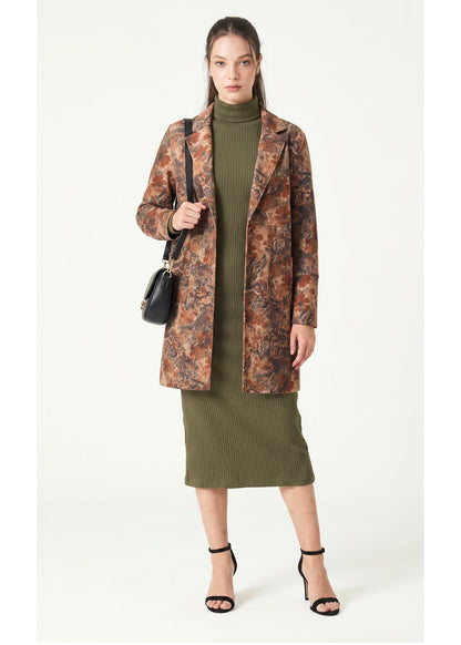 Woman wearing a patterned coat over a green dress on a white background
