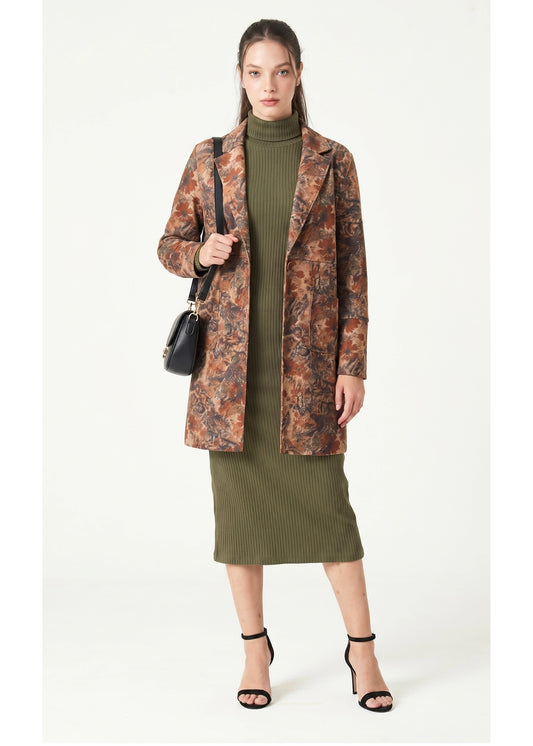 Woman wearing a patterned coat over a green dress on a white background