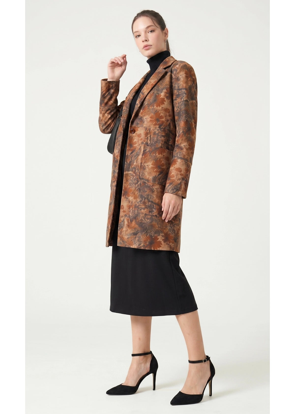 Woman wearing a patterned coat over a black outfit on a white background