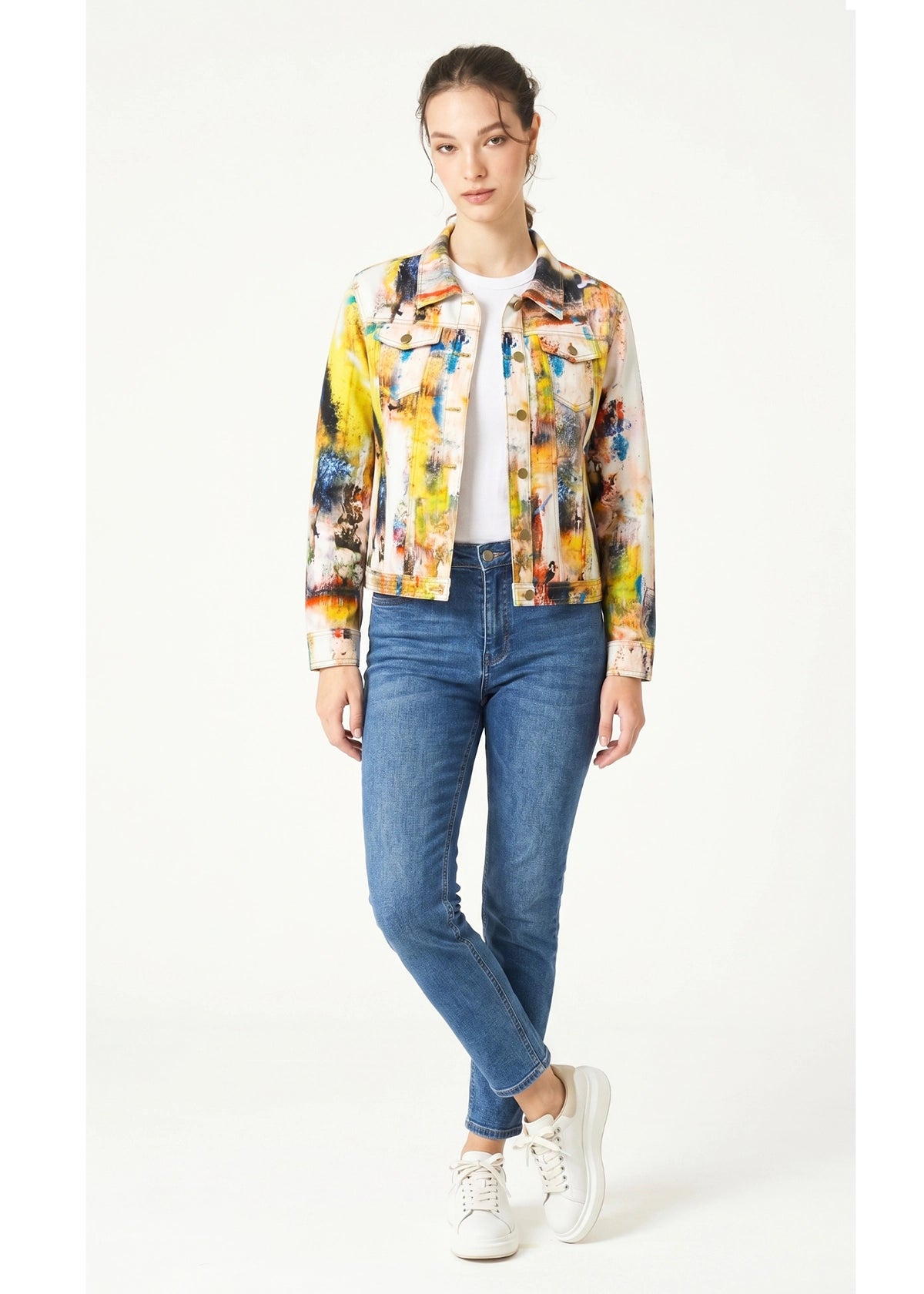 Woman wearing a colorful jacket and blue jeans on a white background