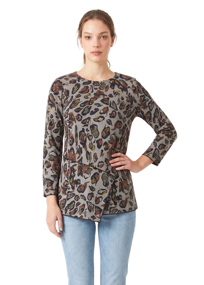 Woman wearing a patterned long-sleeve top and light blue jeans on a white background