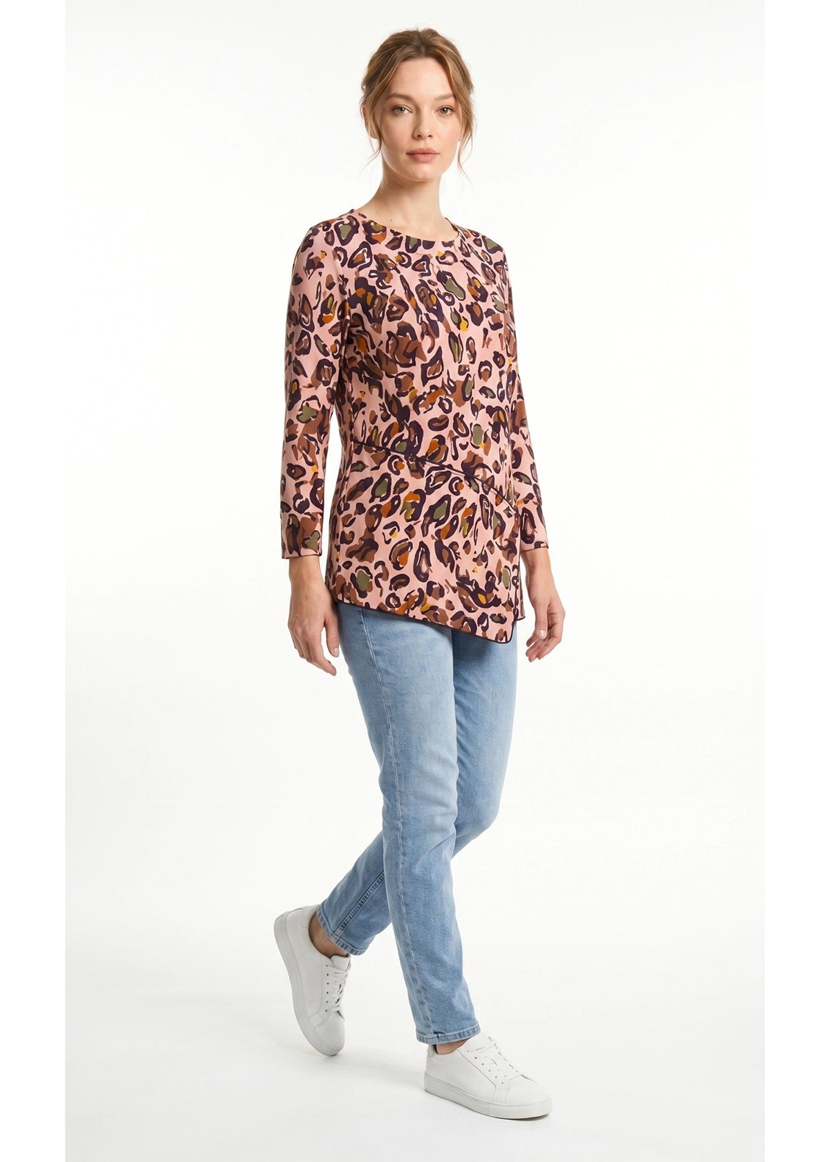 Woman wearing a leopard print top and light blue jeans on a white background