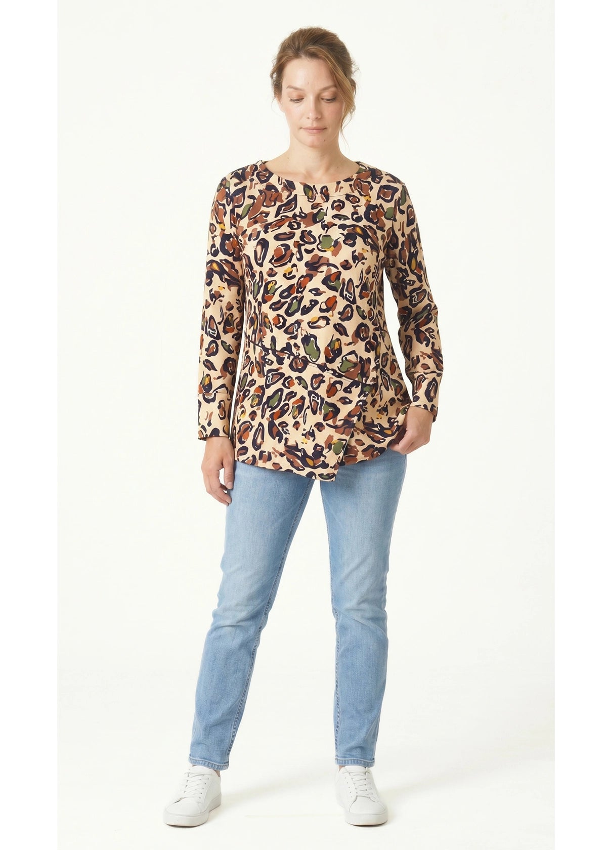 Woman wearing a leopard print top and light blue jeans on a white background