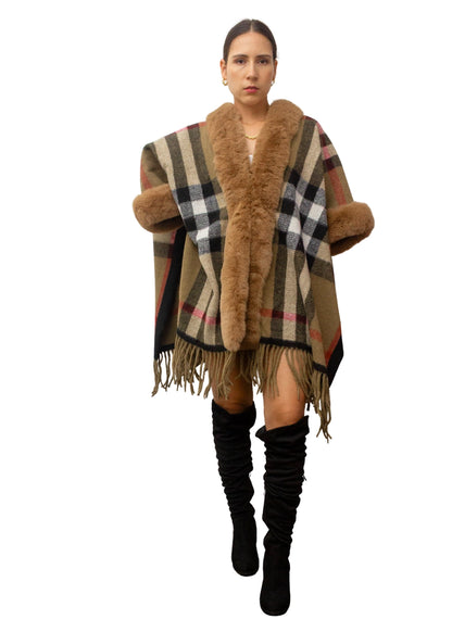 Woman wearing a checkered poncho with fur trim and knee-high boots on a white background
