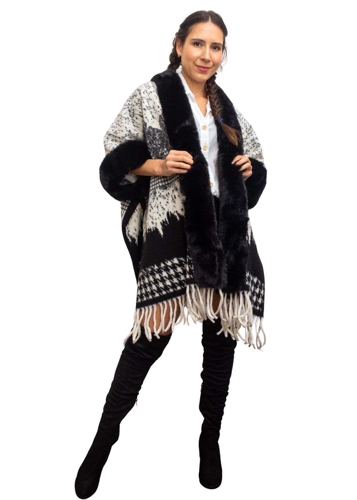 Woman wearing a black and white patterned poncho with fringe on a white background