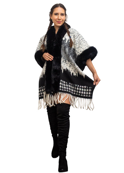 Woman wearing a black and white patterned poncho with fringe on a white background